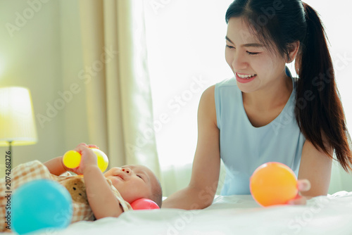 Foto Heartwarming moment love and bonding between mother and her eight month old son in their cozy bed surrounded by brightly colored balls that aid in development provide fun in a joyful atmosphere