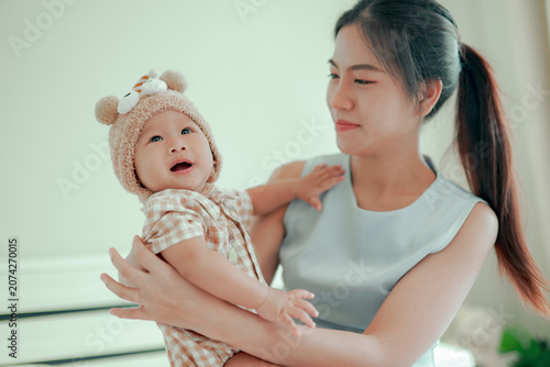 Cuadro en lienzo Young mother gently cradles her adorable baby in her arms on a comfortable bed at home capturing moment of love warmth smiles and happiness