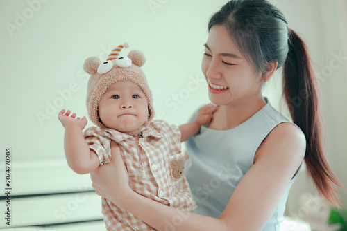Photos Young mother gently cradles her adorable baby in her arms on a comfortable bed at home capturing moment of love warmth smiles and happiness