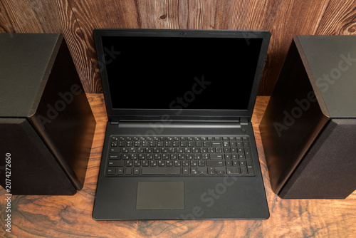 front view of an open laptop and acoustic speakers