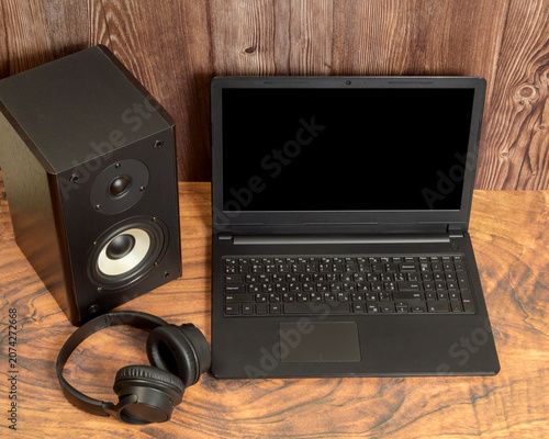 headphones lie on the table in front of the laptop and sound speaker