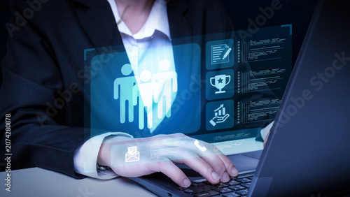 Futuristic Data Analysis: A business person interacts with a holographic interface displaying human resource icons, charts, and award symbols, signifying modern data management and analytics.