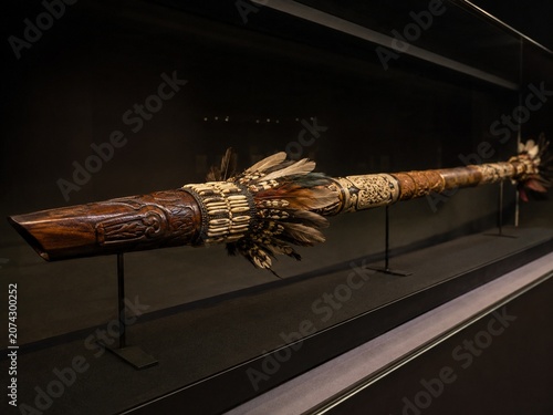 An ornate ceremonial blowpipe displayed in a museum case.