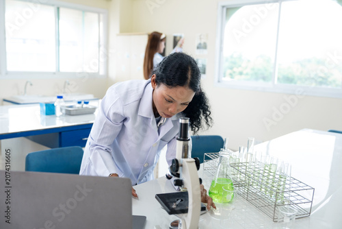 African American female scientist working with microscope and notebook computer in laboratory