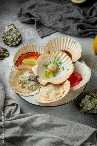 Vertical seafood platter with baked scallops in shells, melted cheese, sauces, herbs, lemon and rustic grey restaurant styling