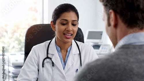 Female doctor in a white coat consults with an unrecognizable male patient in a modern clinic setting, healthcare discussion, medical examination, patient care