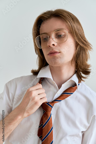 фотографія Young handsome man showcasing elegance with long hair and stylish attire in a mo