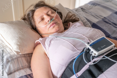Vászonkép Woman resting in bed with home medical monitoring device, nasal cannula oxygen,