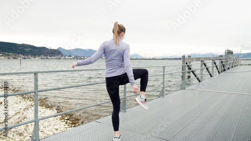 Athletic woman warming up outdoors on a pier