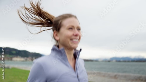 Happy athletic woman running outdoors near lake