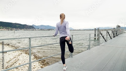 Fit woman stretching leg on a pier before running