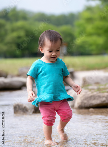 Happy Toddler Walking Barefoot in a Shallow Stream on a Summer Day
