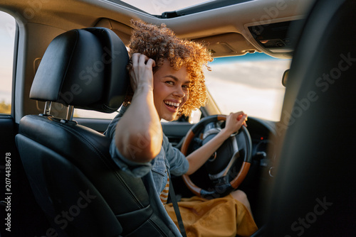 Tableau sur toile Cheerful woman driving, sunlit car interior, relaxed lifestyle moment, candid sm