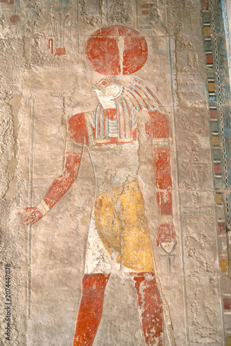 Ancient fresco of Egyptian sun god Ra wearing a sun disk and holding a Ankh symbol in the temple of Hatshepsut, Luxor, Egypt.