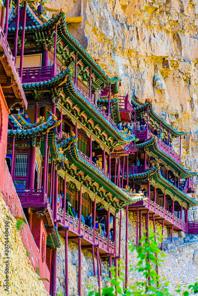 Obraz premium Shanxi, China - May 10 2026: The dramatic façade of Xuankong Temple clings to a sheer cliff, showcasing extraordinary ancient engineering and harmonious integration with the natural landscape