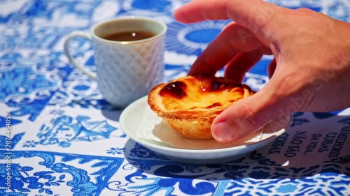 Hand taking and returning traditional Portuguese egg tart on white