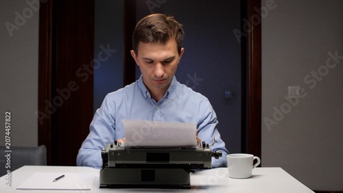 фотографія Man focusing on his work, typing an article or story on a vintage typewriter at