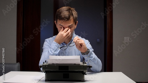 Fotografía Overworked man rubbing his eyes, holding eyeglasses, and feeling exhausted while