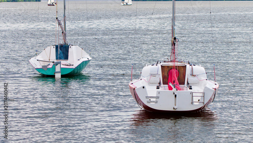 Small sailboats moored on rippling river water during a peaceful summer day. Ideal for concepts of boating, aquatic sports, hobby, and relaxing weekend getaways. Photo
