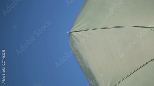 Relax at the beach and enjoy summer weather. An umbrella provides shade from the sun. The sky is clear and blue. This is a perfect spot for rest and fun during vacation.