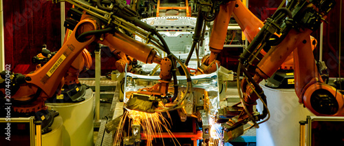 Obraz na płótnie Robotic arms at an auto factory are welding car bodies.
