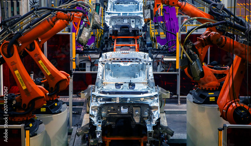 Fotografía Robotic arms at an auto factory are welding car bodies.