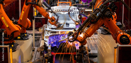 Foto Robotic arms at an auto factory are welding car bodies.