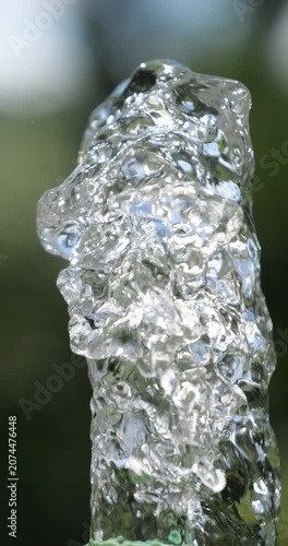 Water jet. Top of water fountain. Flow of pure spring water on a green natural background.