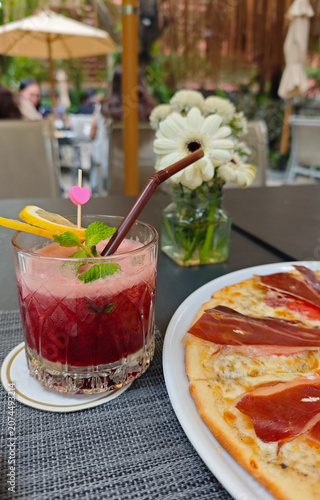 Fotografía Red berry cocktail with mint and lemon on a restaurant terrace table near pizza