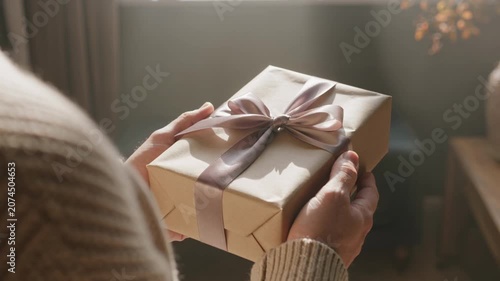 Warm Close Up of Hands Holding a Thoughtfully Wrapped Gift Box, Symbolizing Generosity and Appreciation