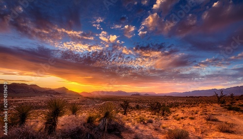 Vibrant Golden Sky With Dramatic Clouds Over A Desert Landscape Creating A Warm And Captivating Atmosphere