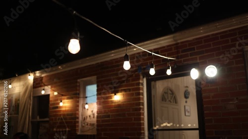 Warm string lights outside brick house at night