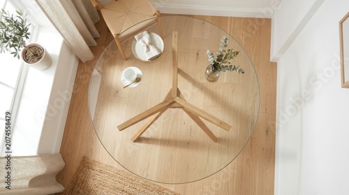 Table with a Minimalist, Round Glass Top and a Stylish Wooden Base, Featuring a Woven Chair and Simple Décor.