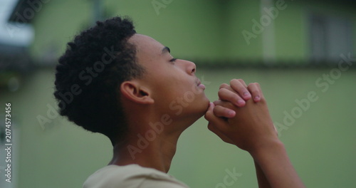 Obraz na plátně Teenage boy clasping hands in prayer, eyes closed in deep devotion, connecting w