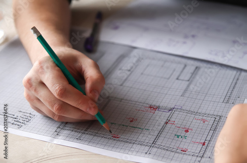 Architect hands drawing blueprint floor plan with pencil close up. Engineer sketching house renovation project layout on graph paper, architectural design or construction planning concept
