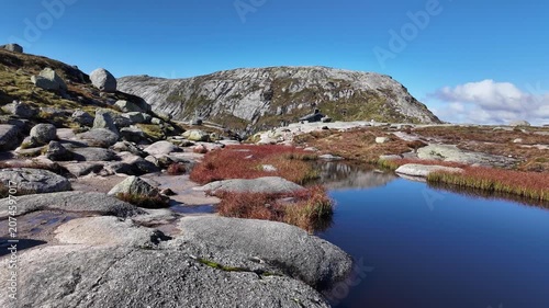 Scenic Mountain Tarn With Red Autumn Vegetation and Granite Boulders on Kjerag Plateau Norway