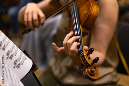 Close up of a musician playing violin during an orchestra performance
