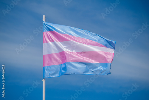 Trans flag colors and transgender pride flag wave above Lisbon, Portugal for an LGBT equality celebration, photographed in a simple outdoor scene