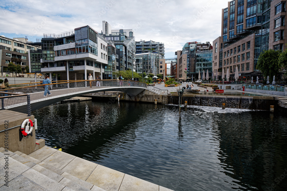 Fototapeta premium Aker Brygge Waterfront, Oslo: Modern Architecture and Pedestrian Bridge