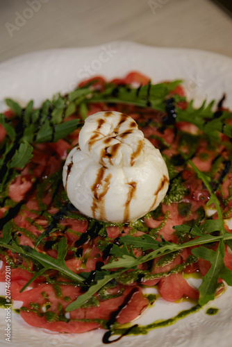 Macro shot of burrata cheese ball with balsamic glaze on fresh salad