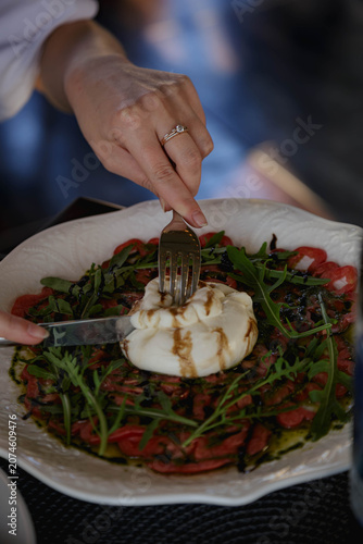Person cutting burrata cheese with knife and fork