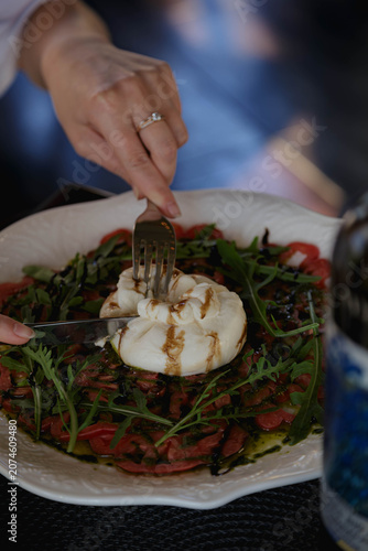 Close up of slicing burrata cheese with arugula