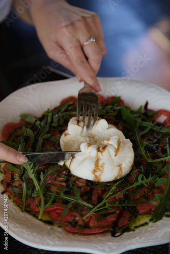 Cutting a fresh burrata cheese with a knife and fork