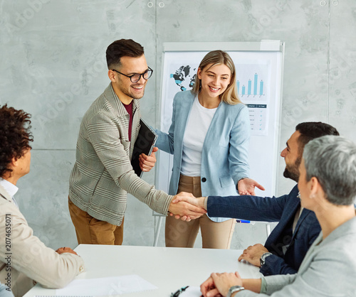 Photography portrait of  a young businessman and businesswoman shaking hands introducing eac