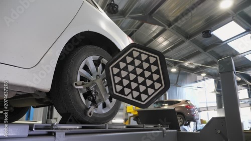 Diagnostics and balancing of wheels on a lift at a close-up view at a modern service station. The car moves slowly with wheel balancing equipment.