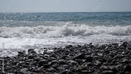 View of large waves in slow motion. Dirty waves rise and break on the rocky shore, forming foam. The sea during a storm.