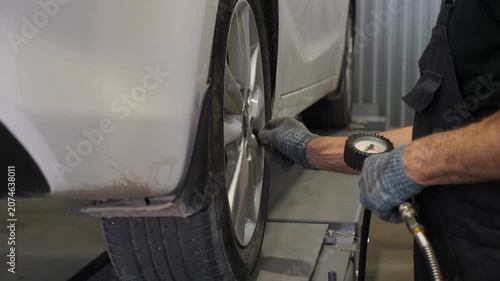 A mechanic checks the tire pressure of a car at a service station or car repair and maintenance facility. If necessary, the mechanic will replace the tires on the vehicle. 