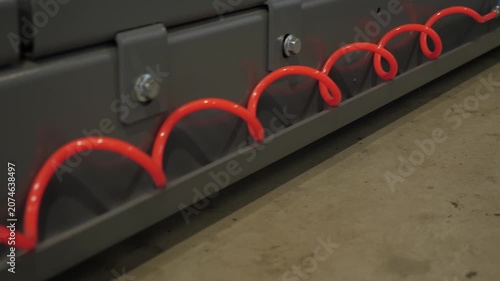 Close-up of a red spiral wire at a car service station. Tire service. A red spiral stretches along the gray car to pump air into tires. Spiral wire for fitting tires.