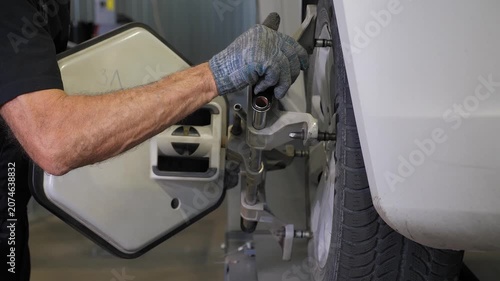 Installation of wheel balancing equipment at a modern service station: A locksmith tightens bolts on the wheel. Wheel balancing and wheel alignment.
