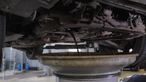 Close-up of the bottom after the oil change with a jet of water at the service station. The mechanic washes the car's bottom with a special tool.